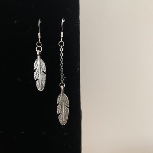 Des boucles d'oreilles asymétriques croix ou plume